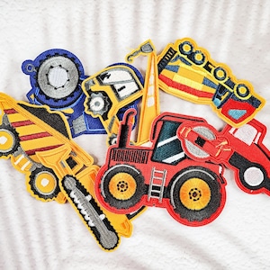 May include: A collection of colorful embroidered patches featuring various construction vehicles. The patches include a blue dump truck, a yellow excavator, and a red tractor, all with detailed stitching and vibrant colors. These patches are perfect for decorating clothing or accessories.