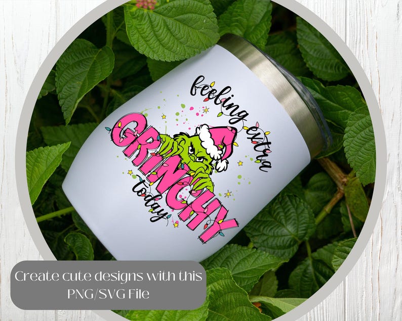 May include: A white insulated tumbler with a stainless steel rim features a Grinch design in pink and green, with the words "feeling extra Grinchy today." The tumbler is surrounded by green foliage.