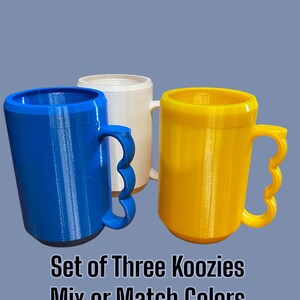 K&ouml;nnte beinhalten: Drei farbige Getr&auml;nkek&uuml;hler in Blau, Wei&szlig; und Gelb, jeweils mit einem einzigartigen Griffdesign. Der Text "Set of Three Koozies Mix or Match Colors" ist darunter zu sehen. Die K&uuml;hler sind zylindrisch und scheinen aus Kunststoff zu sein.