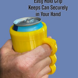 K&ouml;nnte beinhalten: Ein gelber Dosenhalter mit Griff, der eine silberne und blaue Dose h&auml;lt. Der Halter hat Fingerschlaufen f&uuml;r eine einfache Handhabung. Der Text auf dem Bild lautet: "Easy Hold Grip Keeps Can Securely in Your Hand."