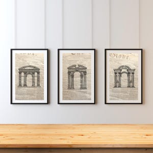 May include: Three black framed prints of architectural drawings of arches on a white wall. The drawings are on a newspaper background.
