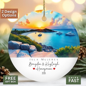 May include: A round ceramic ornament featuring a vibrant sunset over a tropical bay with boats, rocky shores, and lush greenery. The lower white section displays the text: ISLA MUJERES, Brayden & Kayleigh, Honeymoon, and the year 2025.