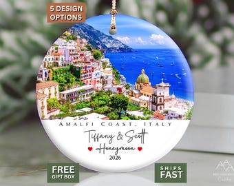 May include: A round ceramic ornament featuring a vibrant coastal landscape of the Amalfi Coast, Italy. The lower white section displays the text "AMALFI COAST, ITALY", "Tiffany & Scott", "Honeymoon" with two red hearts, and the year "2026".