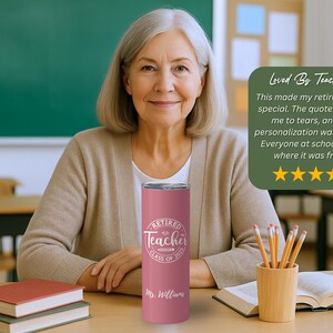 May include: A pink insulated tumbler with the text "Retired Teacher Class of 2023" and "Mr. Williams" in white. The tumbler is held by a woman in a classroom setting. A green sign says "Loved By Teachers!"
