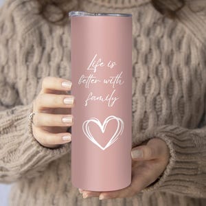 May include: A pink stainless steel tumbler with a white heart and the text "Life is better with family".