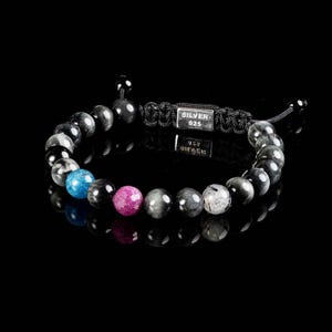 May include: A black and grey beaded bracelet with a silver charm that says "SILVER 925". The bracelet has a blue, pink, and grey bead.