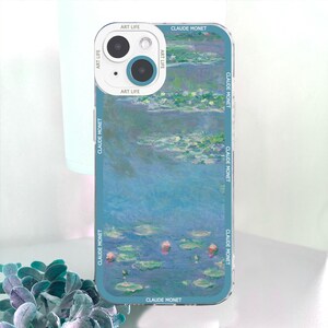 May include: A clear phone case featuring a Claude Monet painting of water lilies. The case has a teal border with the text "CLAUDE MONET" and "ART LIFE" printed on it. The phone's camera is visible in the upper left corner.