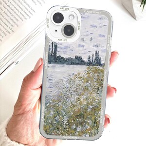 May include: Clear phone case featuring a landscape painting in the style of Claude Monet. The case has a white camera ring with the text "ART LIFE" and "CLAUDE MONET" printed on the sides.