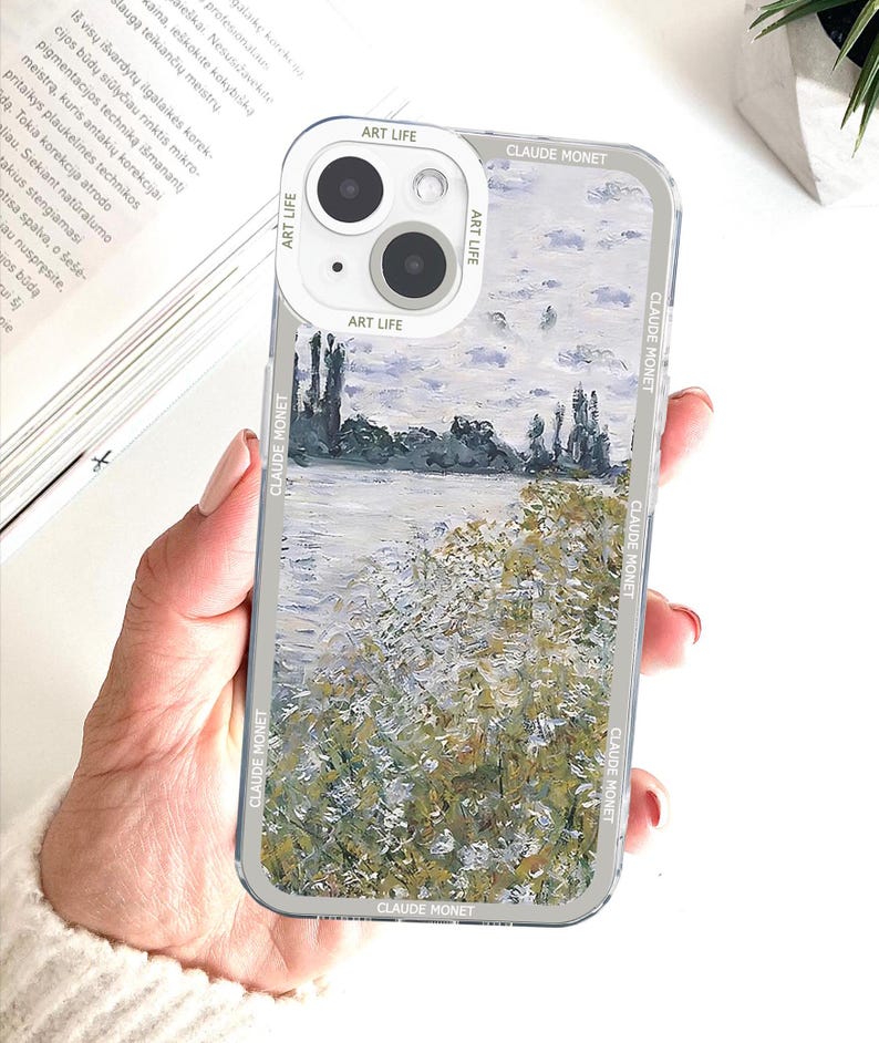 May include: Clear phone case featuring a landscape painting in the style of Claude Monet. The case has a white camera ring with the text "ART LIFE" and "CLAUDE MONET" printed on the sides.