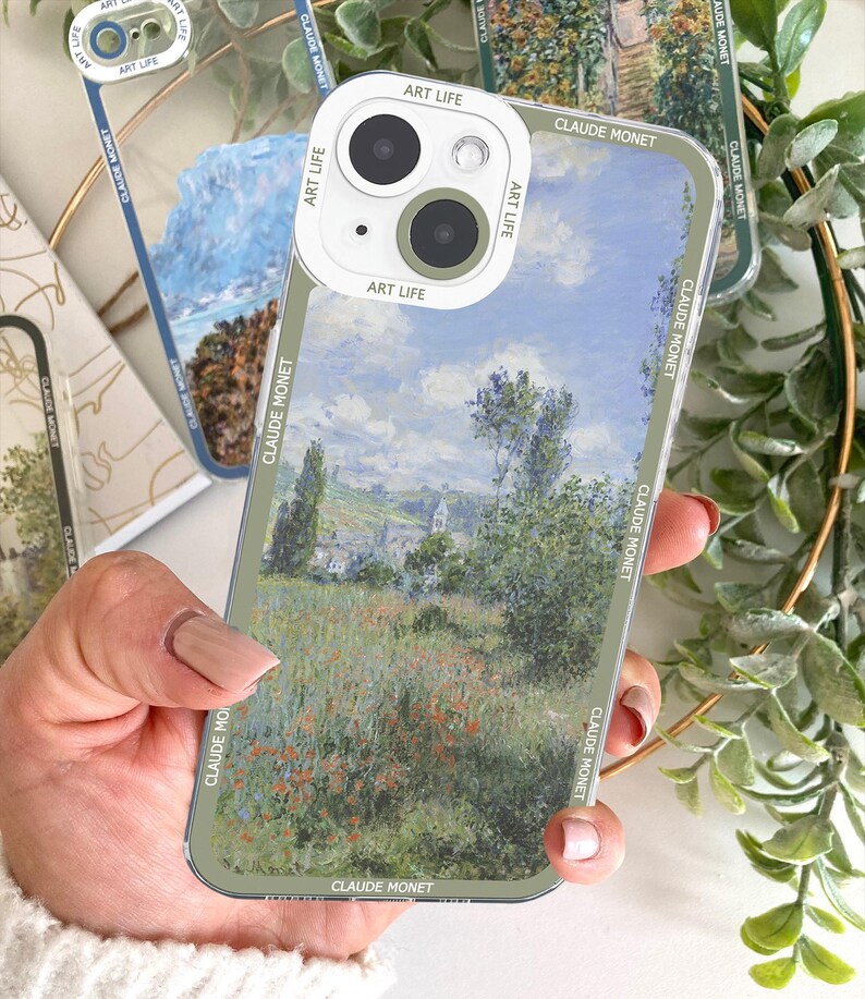 May include: Clear phone case featuring a Claude Monet painting of a landscape with a field of red flowers. The case has a green border with the text "CLAUDE MONET" and "ART LIFE" printed on it. The phone's camera is visible.