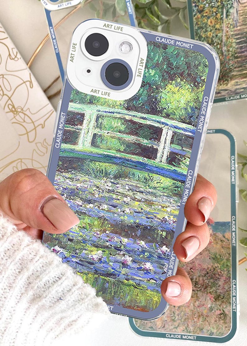 May include: Clear phone case featuring a painting by Claude Monet. The case showcases a bridge over water with lily pads, in shades of green, blue, and white. The case has the words "ART LIFE" and "CLAUDE MONET" printed on it.