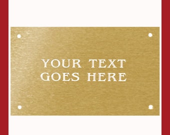 May include: A gold-colored metal plaque with four holes for hanging. The plaque has the text "YOUR TEXT GOES HERE" engraved in white.