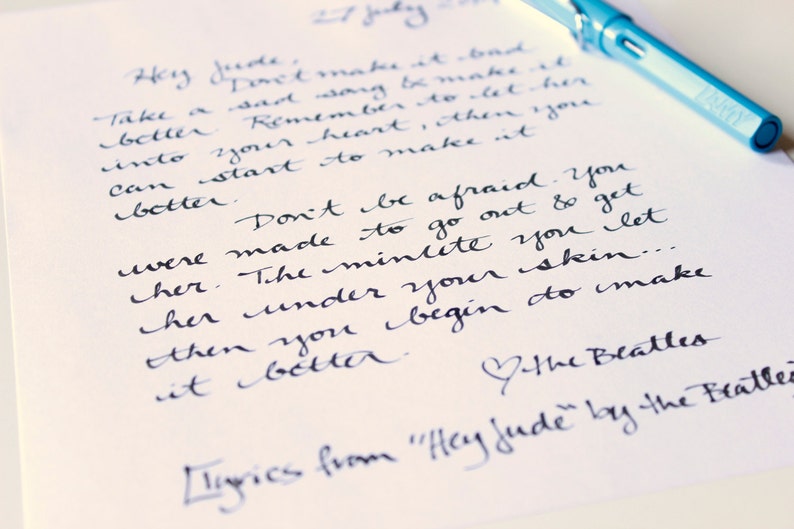 May include: Handwritten lyrics from the song "Hey Jude" by The Beatles. The lyrics are written in black ink on white paper. The lyrics are about overcoming sadness and letting someone into your heart.