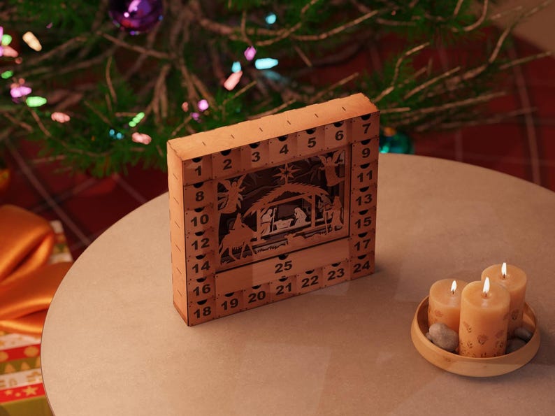 Light wooden nativity advent calendar placed on a round table near lit candles and a decorated Christmas tree.