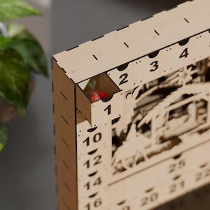 Close-up of a light wooden advent calendar with one numbered drawer pulled open to reveal a wrapped candy inside.