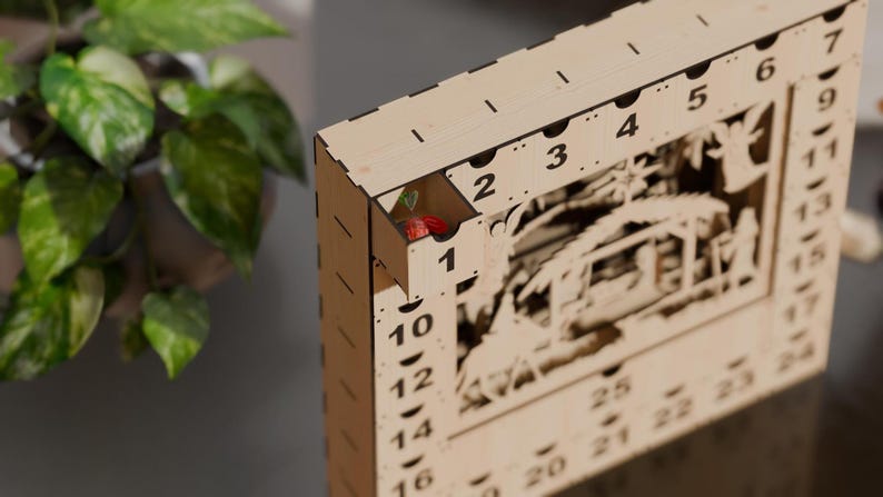 Close-up of a light wooden advent calendar with one numbered drawer pulled open to reveal a wrapped candy inside.