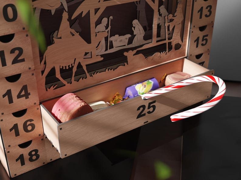 Close-up of the pulled-out bottom drawer number 25 of a wooden advent calendar, revealing various candies and a candy cane.