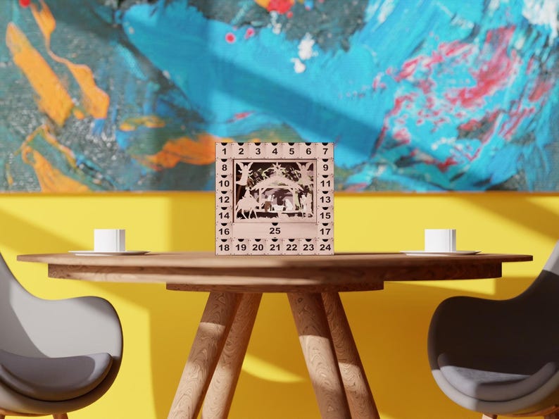 Light wooden nativity advent calendar centered on a wooden dining table between two chairs against a colorful painted wall.