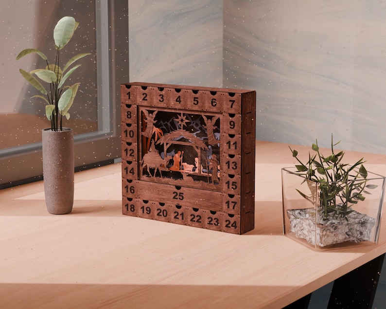 Dark wooden nativity advent calendar sitting on a wooden desk next to potted plants and a window.