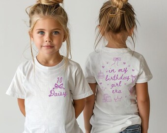 May include: White t-shirt with a pink design on the front that says "10 Daisy" with a pink bow. The back of the shirt has a pink design that says "in my birthday girl era" with a pink bow, cake, crown, and gifts.