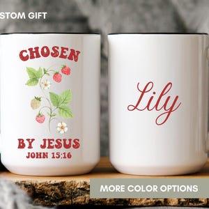 May include: White ceramic mug with a black rim and handle. The mug has a red and green illustration of a strawberry plant with the text "Chosen by Jesus John 15:16". The mug also has the name "Lily" written in red cursive.