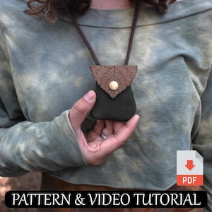 Op de afbeelding: Een groene leren tas met een bruin bladerenontwerp hangt aan een bruin koord. De tas wordt in een hand gehouden met een ring aan de vinger. De tekst "PATTERN & VIDEO TUTORIAL" staat onderaan de afbeelding. Een PDF-downloadpictogram bevindt zich in de rechterbenedenhoek.