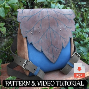Może przedstawiać: Brązowa skórzana torba z klapą w kształcie liścia i niebieską podszewką z tkaniny. Torba ma dwa brązowe skórzane paski i metalową klamrę. Torba leży na drewnianej powierzchni. PATTERN & VIDEO TUTORIAL