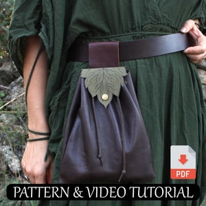 Puede incluir: Una bolsa de cuero marrón con cierre de cordón, sujeta a un cinturón marrón. La bolsa tiene una solapa decorativa en forma de hoja con un botón dorado. El texto "PATTERN & VIDEO TUTORIAL" es visible en la parte inferior.