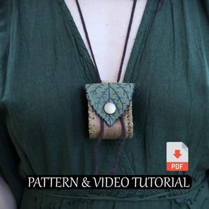 Puede incluir: Un pequeño collar de bolsa de cuero hecho a mano con un diseño de hoja en la solapa, asegurado con un botón. La bolsa está unida a un cordón oscuro. El texto "PATTERN & VIDEO TUTORIAL" es visible. El fondo es un vestido verde.