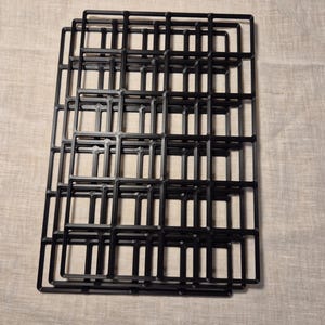 May include: A stack of black metal square-shaped frames. The frames are stacked on top of each other, creating a grid pattern.