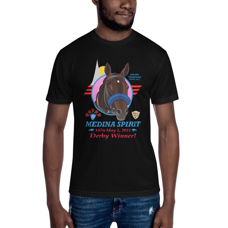 Puede incluir: Camiseta negra con un gr&aacute;fico de cabeza de caballo y el texto "MEDINA SPIRIT Derby Winner!" en rojo y azul. El dise&ntilde;o incluye un c&iacute;rculo rosa, rayas rojas y blancas y las palabras "Racing Tradition Since 1875."