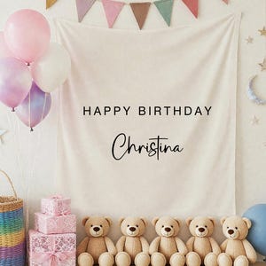 Op de afbeelding: Een verjaardagsscène met een banner met de tekst "HAPPY BIRTHDAY Christina". De scène omvat ballonnen, teddyberen, geschenkdozen en een regenboogmand. Een blauwe ballon staat rechts.