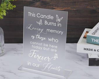 以下が含まれることがあります： 「This Candle Burns in Loving Memory of Those Who Cannot Be Here Today But Are Forever in Our Hearts」というテキストと蝶の模様が刻まれた透明なアクリル製のメモリアルキャンドルホルダーです。