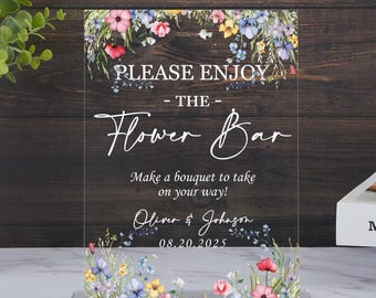 May include: Clear acrylic sign with floral accents and the text "PLEASE ENJOY - THE - Flower Bar". The sign includes the text "Make a bouquet to take on your way!" and the names "Oliver & Johnson" with the date "08.20.2025".