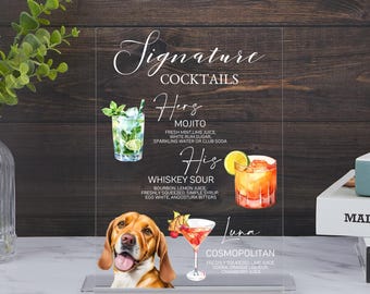 May include: A clear acrylic sign with a watercolor illustration of cocktails and a dog. The sign reads "Signature Cocktails" and lists three cocktails: "Mojito", "Whiskey Sour", and "Cosmopolitan".