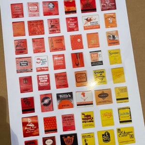 May include: A collection of 49 vintage matchbook covers, mostly red, with various business names and logos. The matchbooks are arranged in a grid on a white background.