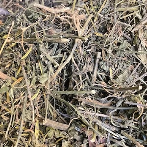 Könnte beinhalten: Eine Ansammlung von getrocknetem Pflanzenmaterial, bestehend aus einer dichten Mischung aus dünnen braunen holzigen Stängeln, kleinen dunkelgrünen getrockneten Blättern und faserigen Pflanzenfragmenten. Die Textur ist spröde und unregelmäßig.