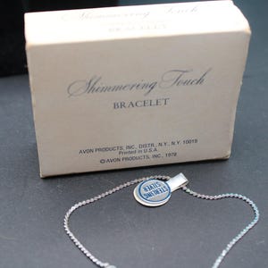May include: A silver-toned chain bracelet with a round tag reading STERLING SILVER, accompanied by a rectangular off-white box labeled Shimmering Touch BRACELET, AVON PRODUCTS, INC., DISTR., N.Y., N.Y. 10019, Printed in U.S.A. © AVON PRODUCTS, INC., 1978.