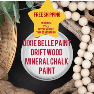 May include: A jar of Dixie Belle Driftwood Mineral Chalk Paint is the focal point, surrounded by decorative elements. The image includes a woven basket, wooden beads, and a star-shaped graphic with text.