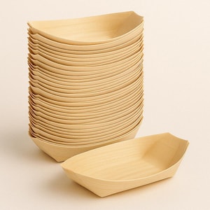 Op de afbeelding: Een stapel lichtgekleurde houten bootvormige serveerbakjes. Eén bakje staat los van de stapel. De bakjes hebben een natuurlijke houtnerf en zijn ontworpen voor het serveren van voedsel. De bakjes zijn ongeveer 18 cm lang.