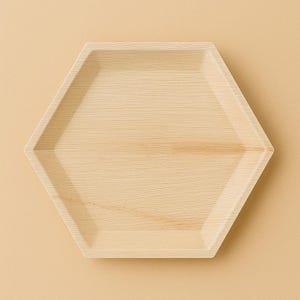 May include: A hexagonal, light brown, wooden serving tray. The tray is made from natural materials and has a smooth, slightly textured surface.
