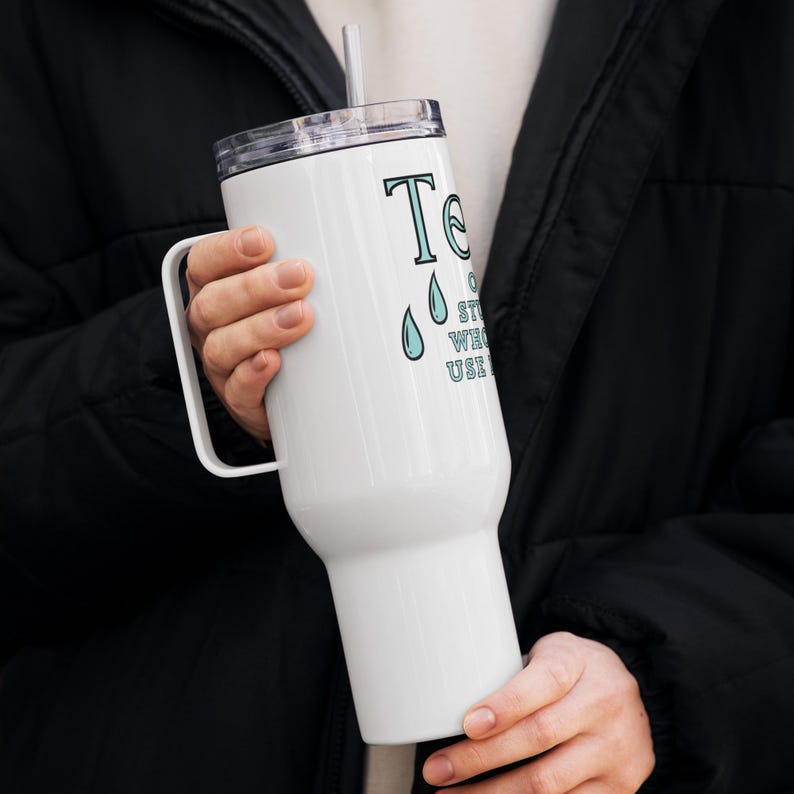 May include: White stainless steel travel mug with a black lid and handle. The mug features a blue and white graphic that says "Tears of a strong woman who uses her voice".