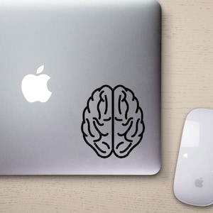 Könnte beinhalten: Ein silberner Laptop mit einem schwarzen Gehirn-Aufkleber auf der rechten Seite des Deckels. Das Apple-Logo befindet sich auf der linken Seite des Deckels.
