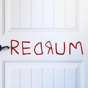 Puede incluir: Una puerta blanca con una manija de puerta negra. La palabra "REDRUM" está escrita en rojo en la puerta.