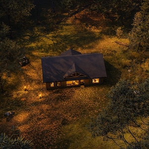 Aerial twilight view of a black cottage cabin showing a 2 bedroom 2 bathroom 1200 sqft modern house plan surrounded by forest, warm glowing windows, autumn leaves on the ground, and soft pathway lighting.