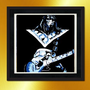May include: A framed art print featuring a stylized illustration of a musician playing a blue electric guitar. The artwork is in shades of blue and white against a black background. The print is in a black frame.