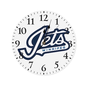 Op de afbeelding: Witte klok met zwarte wijzers en een blauw-wit Winnipeg Jets logo. Het logo zegt "Jets" met "Winnipeg" eronder.