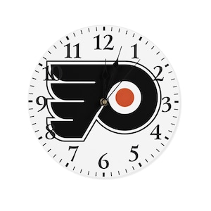 May include: A round wall clock with a white face featuring the Philadelphia Flyers logo in black and orange. The clock has black numerals and hands, with a second hand. The clock is a decorative item for a sports fan.