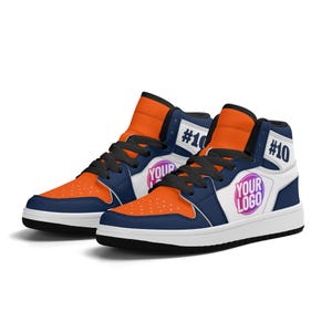 May include: A pair of high-top sneakers with a white, orange, and navy blue color scheme. The shoes have a black lace-up closure and a white sole. The right shoe has a pink and purple circle with the text "YOUR LOGO" on the side. Both shoes have the number "#10" on the side.