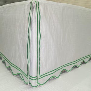 Może przedstawiać: Biała spódnica na łóżko z falbanką i podwójną zieloną lamówką.